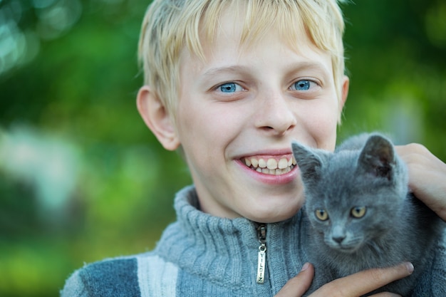 Ein Junge spielt mit einem Kätzchen im Garten