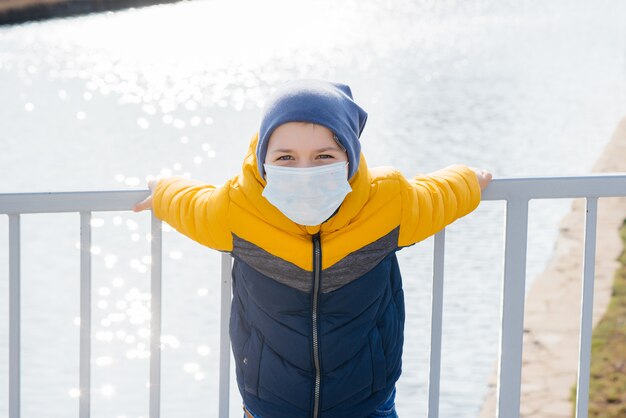 Ein Junge steht auf einem grauen Hintergrund in einer Maske während einer Quarantäne mit freiem Raum. Quarantäne in der Maske.