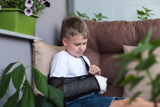 Ein Junge streckt eine Armschlinge an einem gebrochenen Arm