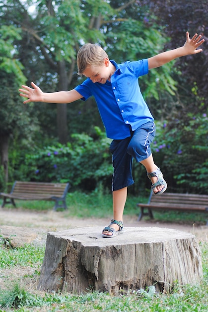 Ein Junge tanzt in voller Länge auf einem Baumstumpf im Park