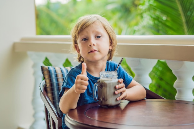 Ein Junge trinkt einen Drink von einem Johannisbrotbaum