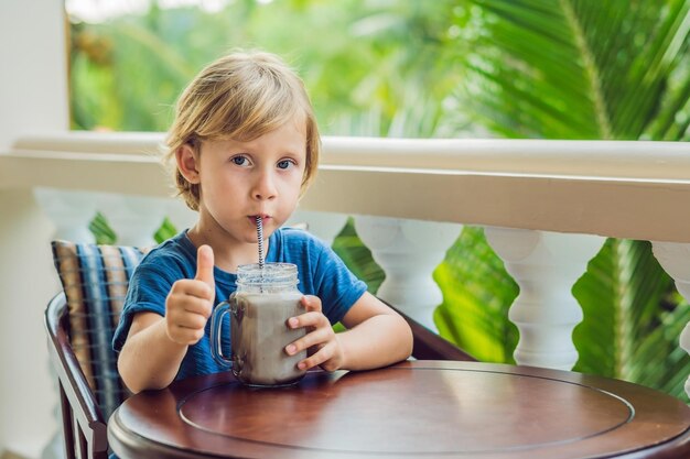 Ein Junge trinkt einen Drink von einem Johannisbrotbaum