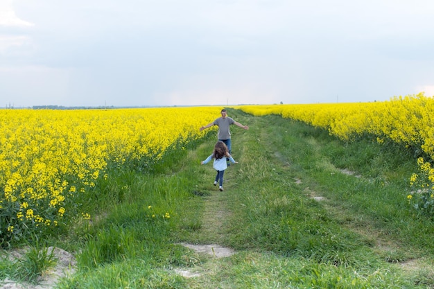 Ein Junge und ein Mädchen laufen durch ein Feld mit gelben Blumen.