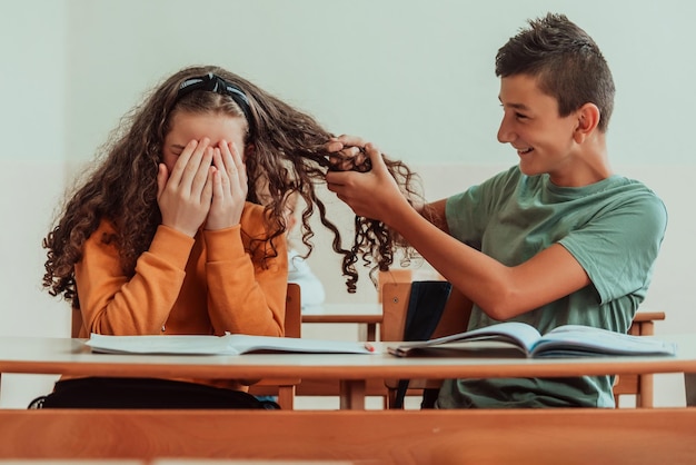 Ein Junge und ein Mädchen sitzen zum Zeitpunkt der Pandemie im Klassenzimmer und spielen mit ihren Haaren Selektiver Fokus Hochwertiges Foto