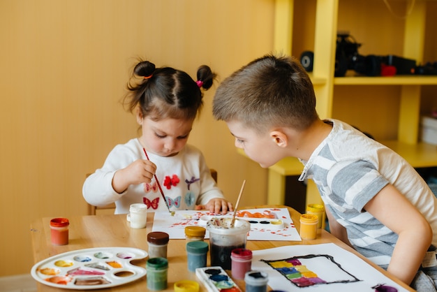 Ein Junge und ein Mädchen spielen zusammen und malen. Erholung und Unterhaltung. Bleib zuhause.