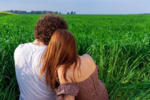 Foto ein junge und ein mädchen umarmen sich auf einem grünen feld. eine romantische fotosession eines verliebten paares auf einem grüne weizenfeld.