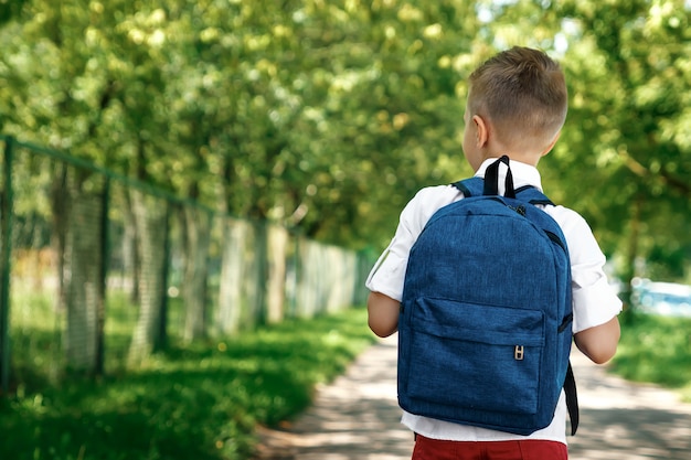 Ein Junge von einer Grundschule mit einem Rucksack auf der Straße