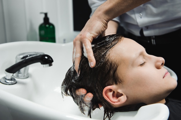 Ein Junge wird vom Friseur im Friseursalon gewaschen.