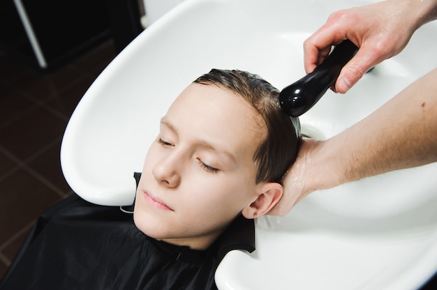 Ein Junge wird vom Friseur im Friseursalon gewaschen.