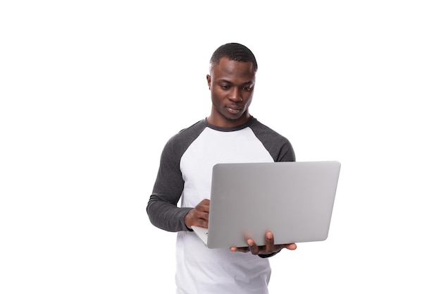 Ein junger afrikanischer Mann arbeitet aus der Ferne auf dem Gebiet von IT und benutzt einen Laptop