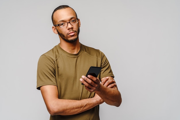ein junger Afroamerikaner, der eine Brille trägt, die Handy hält