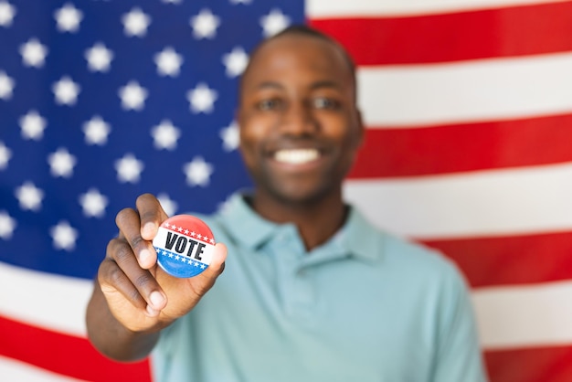 Ein junger afroamerikanischer Mann zeigt einen 39Vote39-Knopf