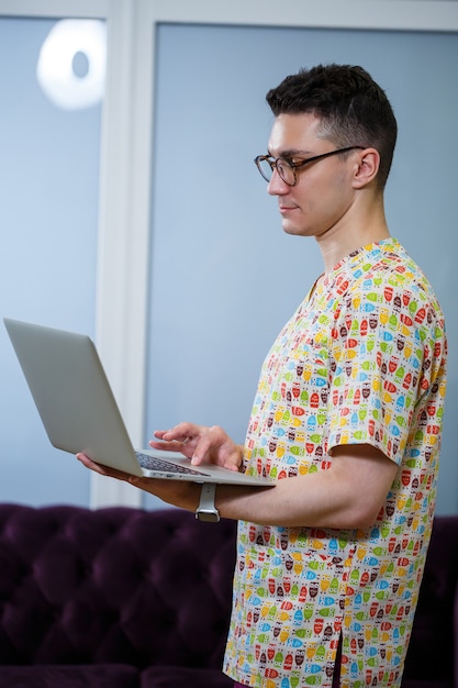 Ein junger Arzt arbeitet an einem Laptop an einer Dissertation. Der Arzt in der Klinik führt die Online-Patientenaufnahme durch