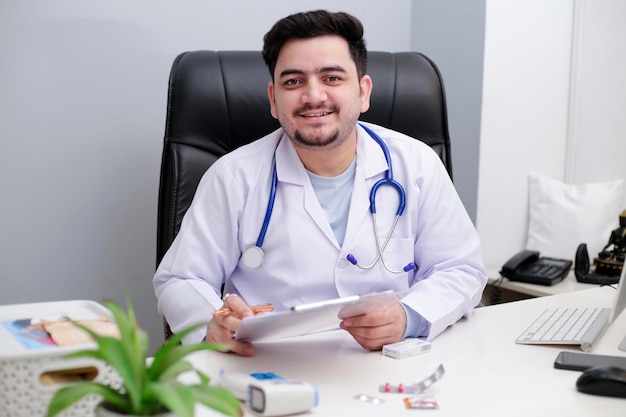 Ein junger Arzt sitzt in der Klinik und hält Notizblock und Stift in der Hand