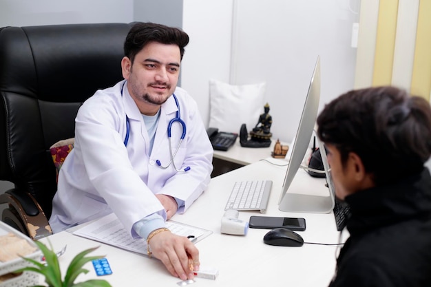 Ein junger Arzt sitzt mit einem Patienten in der Klinik und gibt ihm Medikamente