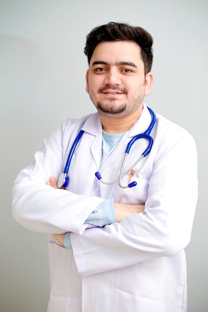Ein junger Arzt steht mit verschränkten Armen da und lächelt