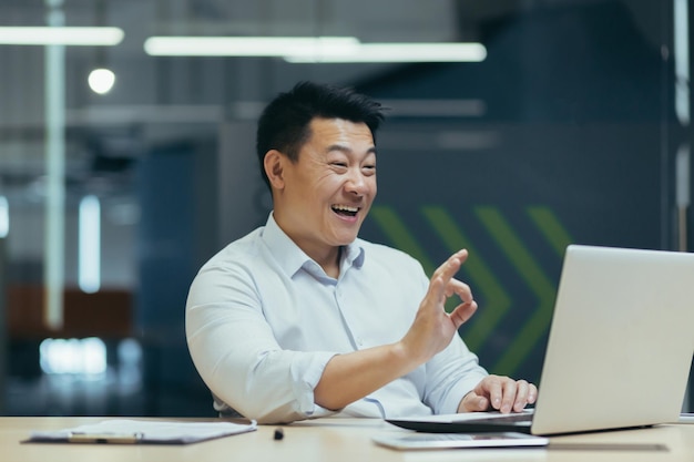 Ein junger asiatischer Geschäftsmann führt ein Online-Interview für einen Job in einem Unternehmen durch, in dem er im Büro sitzt