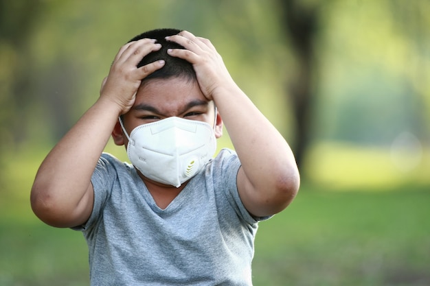 Ein junger asiatischer Junge, 7 Jahre alt, trägt eine Maske zum Schutz vor Staub PM 2.5 und Keimen