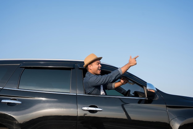 Ein junger asiatischer Mann fährt an einem klaren Tag ein Auto. Mit schönem blauen Himmel. Er fährt, um mit dem Auto zu reisen.