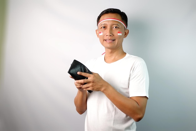 Ein junger asiatischer Mann zeigt einen schockierten Ausdruck, wenn er auf seine leere Brieftasche schaut