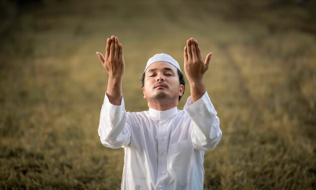 Ein junger asiatischer muslimischer Mann, der bei Sonnenuntergang betetRamadan-Festival-Konzept