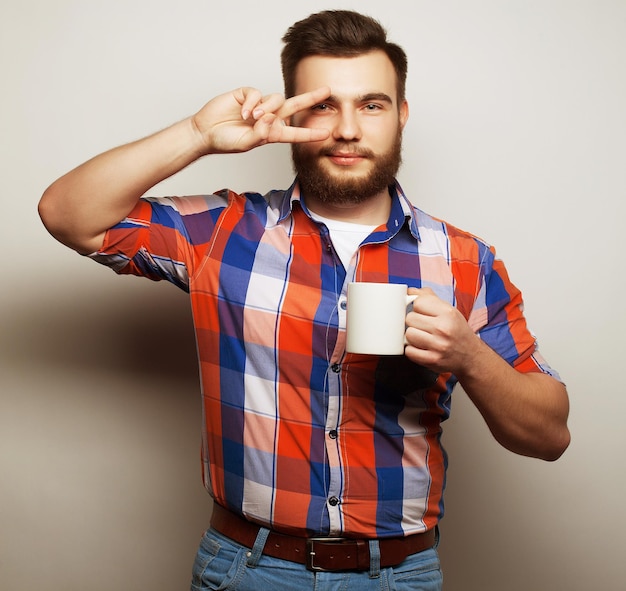 Ein junger bärtiger Mann trinkt eine Tasse Kaffee oder Tee