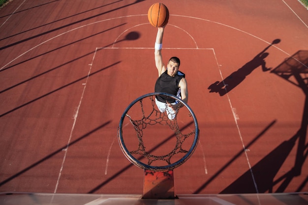 Ein junger Basketballspieler erzielt einen Slam Dunk.