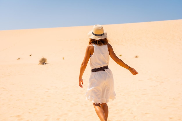 Ein junger europäischer Tourist mit Hut, der durch die Dünen von Corralejo geht