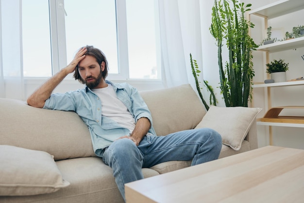 Ein junger freiberuflicher Mann sitzt nach einem anspruchsvollen Job auf der Couch und ruht traurig auf der Cove ab. Hochqualitätsfoto