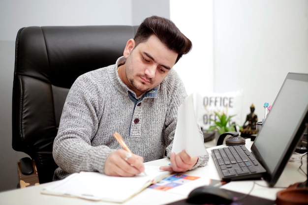 Ein junger Geschäftsmann schreibt mit Stift auf Papier.