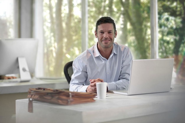 Ein junger Geschäftsmann sitzt im Büro und benutzt einen Laptop