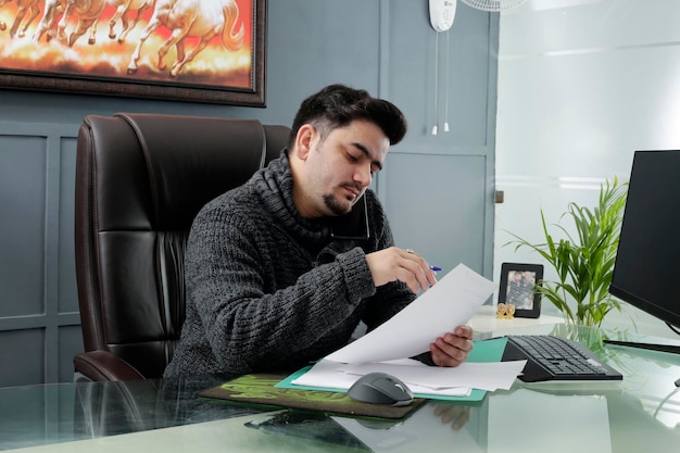 Ein junger Geschäftsmann sitzt im Büro und überprüft einige Dokumente.