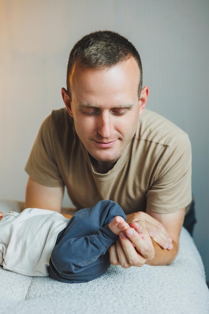 Ein junger, glücklicher Vater küßt seinen kleinen Söhnen die Füße.