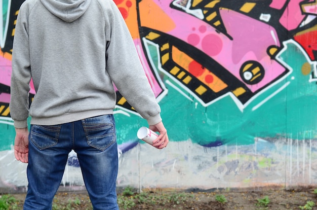 Ein junger Graffitikünstler in einem Hoodie betrachtet die Wand