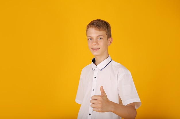 ein junger gutaussehender kerl in einem weißen hemd zeigt einen klasse gelben hintergrund