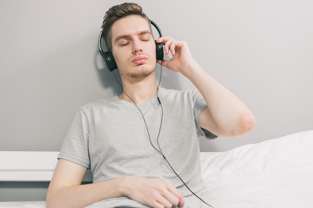 Ein junger gutaussehender Mann auf der Couch, der Musik hört. Zu Hause bleiben