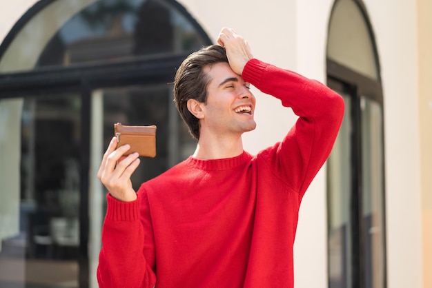 Ein junger gutaussehender Mann, der draußen eine Brieftasche hält, hat etwas erkannt und beabsichtigt, die Lösung zu finden