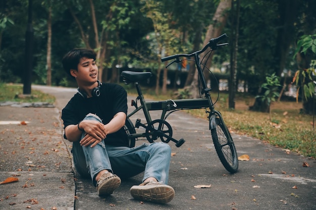 Ein junger, hübscher, bärtiger Mann macht eine Pause, während er mit seinem Fahrrad durch die Stadt fährt und sein digitales Tablet benutzt, um nachdenklich wegzuschauen