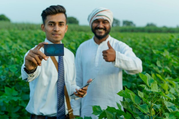 Foto ein junger indischer agronom führt einen bauern auf dem feld mit einer karte in der hand