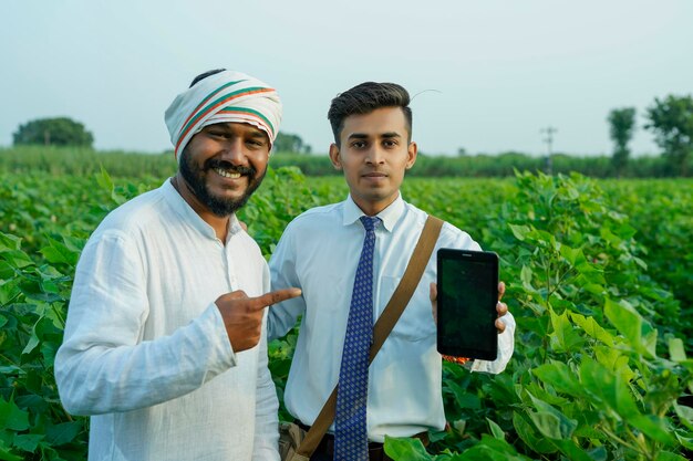 Foto ein junger indischer agronom zeigt einem landwirt auf einem tablett einige informationen auf dem landwirtschaftsfeld