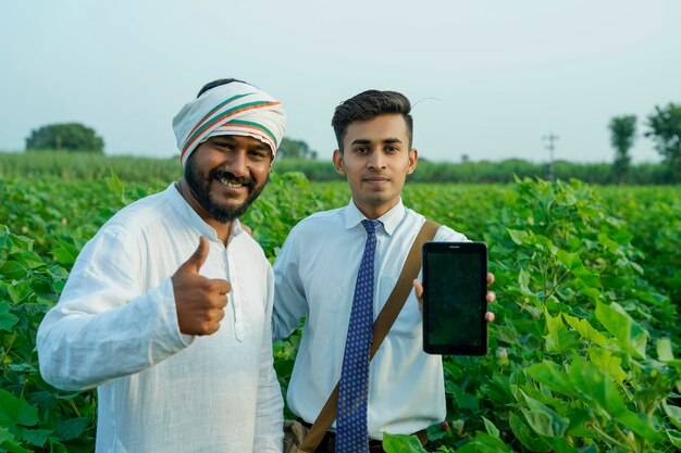 Foto ein junger indischer agronom zeigt einem landwirt auf einem tablett einige informationen auf dem landwirtschaftsfeld