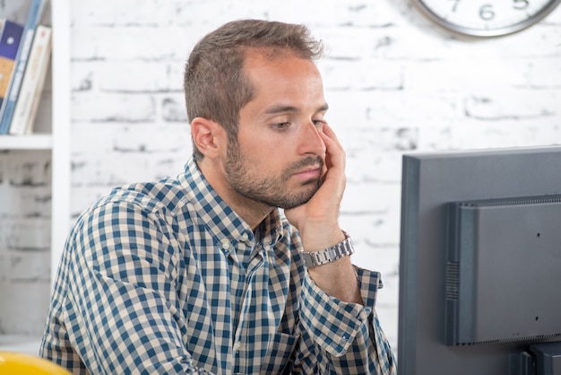 Ein junger Ingenieur nachdenklich an seinem Computer