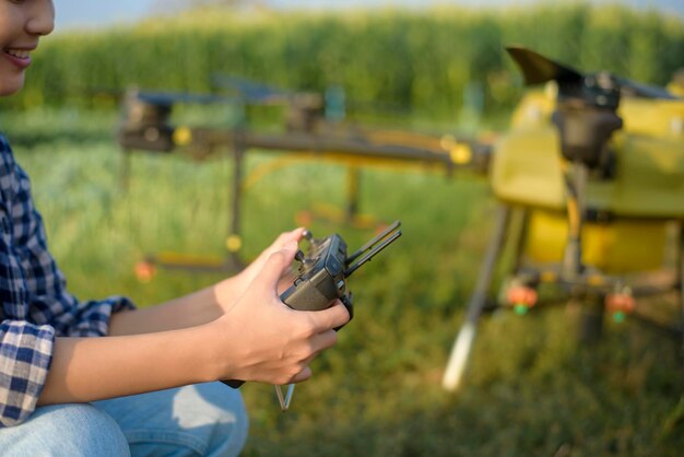 Ein junger intelligenter Landwirt, der Drohnen kontrolliert, die Düngemittel und Pestizide über Ackerland sprühen