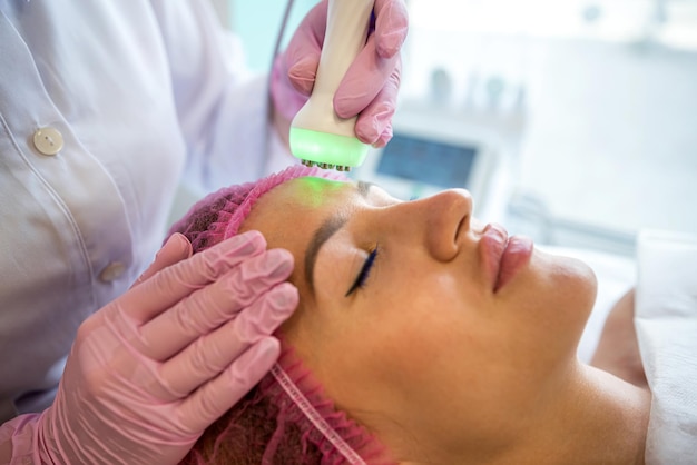 Ein junger Kosmetiker reinigt sein Gesicht in einem Kosmetikbüro Hautreinigung in einem Schönheitssalon Kosmetologe reinigt Akne und Mitesser aus dem Gesicht