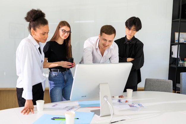 Ein junger männlicher Chef zeigt dem Team ein neues Projekt am Computer