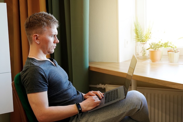 Ein junger männlicher Programmierer arbeitet zu Hause mit einem Laptop