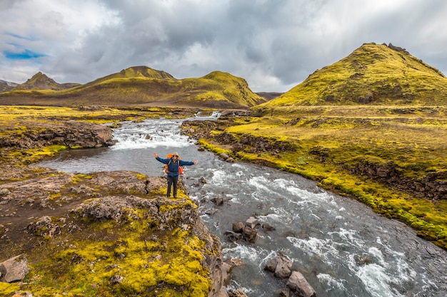 Ein junger Mann an einem großen Fluss von der 54 km langen Wanderung von Landmannalaugar, Island