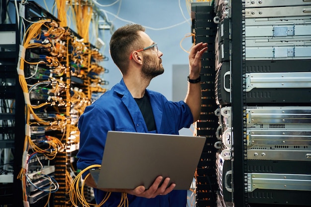 Ein junger Mann arbeitet mit Internetgeräten und Kabeln im Serverraum