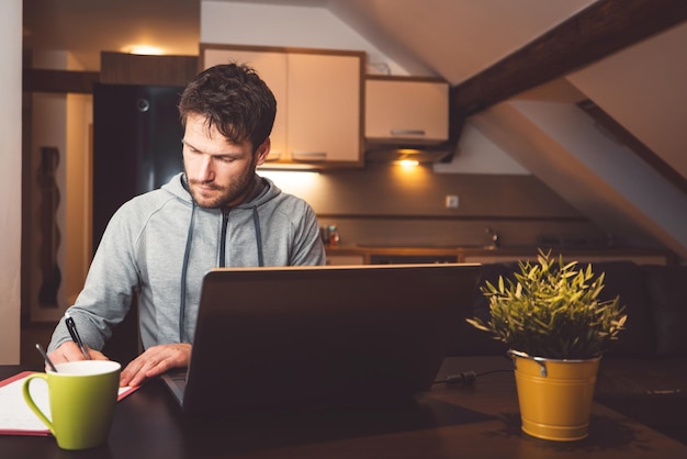 Ein junger Mann benutzt zu Hause einen Laptop
