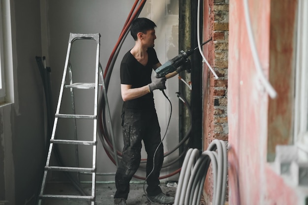 Ein junger Mann bricht mit einem Perforator eine Wand